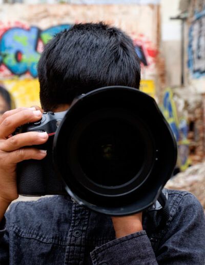 Fotógrafo disparando con un teleobjetivo ante una pared con grafiti