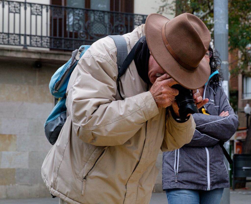 Hombre con sombrero y mochila fotografiando en la calle