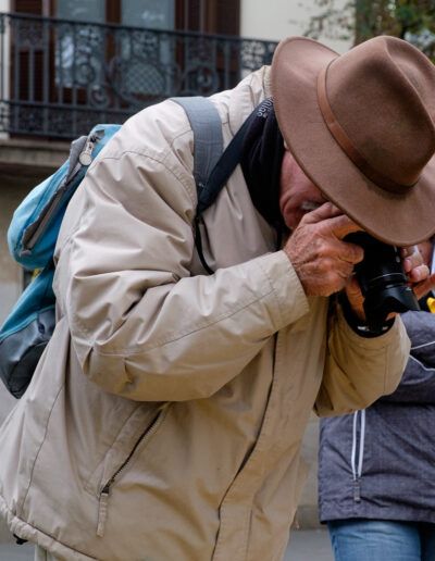 Hombre con sombrero y mochila fotografiando en la calle