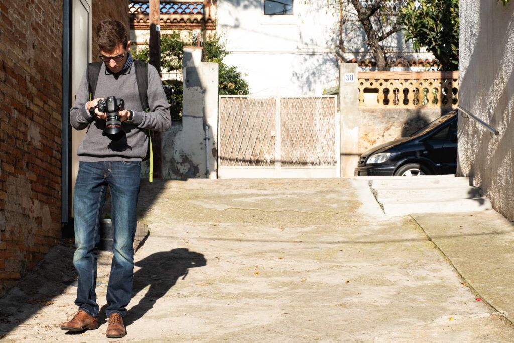 Fotógrafo disparando con su cámara en un callejón iluminado por el sol