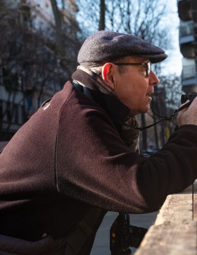 Hombre con gorra fotografiando con un teleobjetivo en la calle
