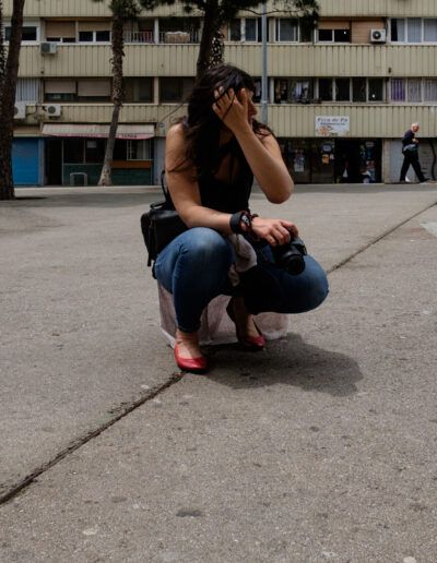 Mujer agachada fotografiando con su cámara en una plaza urbana