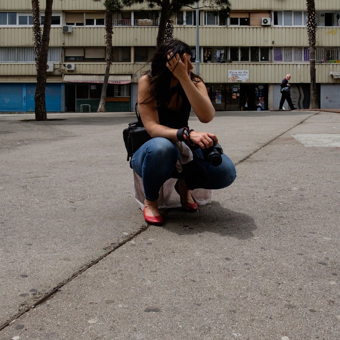 Mujer agachada fotografiando con su cámara en una plaza urbana