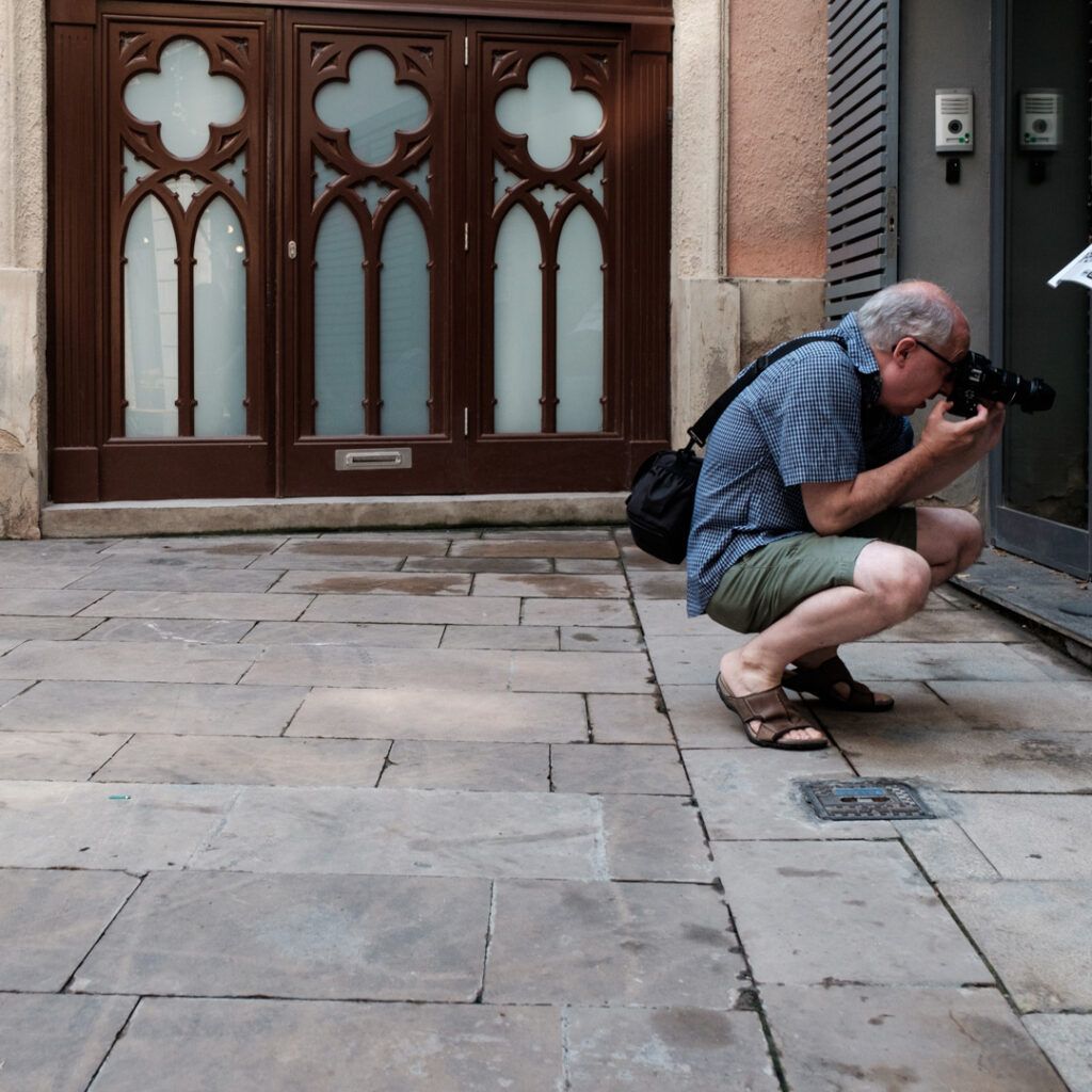 Fotógrafo agachado disparando junto a un edificio de estilo gótico