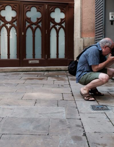 Fotógrafo agachado disparando junto a un edificio de estilo gótico