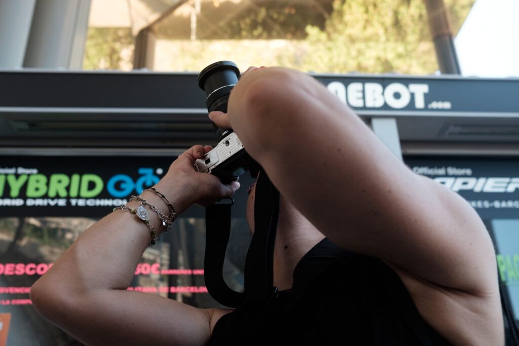 Fotógrafo disparando con su cámara en una calle con un autobús al fondo