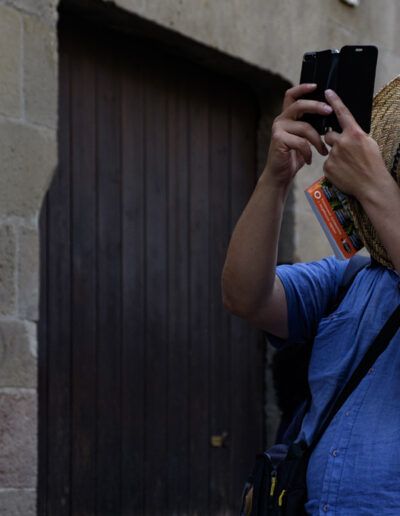 Hombre con sombrero de paja tomando una foto con el móvil junto a una puerta