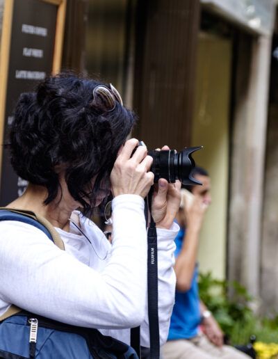 Mujer con mochila fotografiando con su cámara en una calle de Barcelona