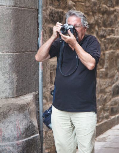 Fotógrafo disparando con su cámara junto a un muro de piedra en Barcelona