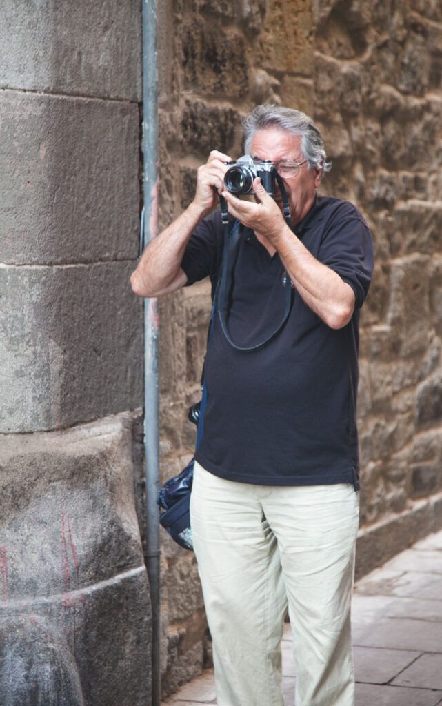 Fotógrafo disparando con su cámara junto a un muro de piedra en Barcelona