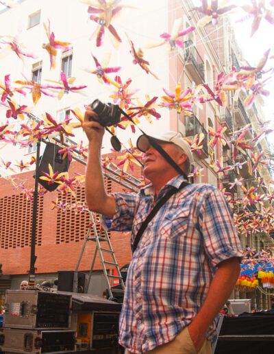 Hombre con camisa de cuadros fotografiando entre adornos de papel rojo