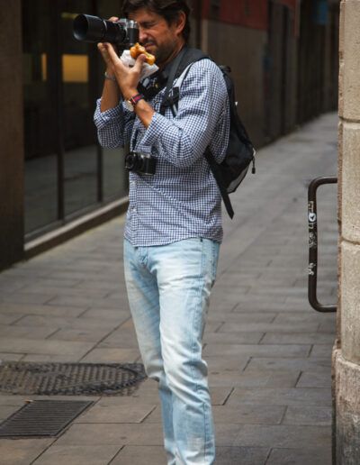 Fotógrafo con vaqueros disparando con su cámara en una calle de Barcelona