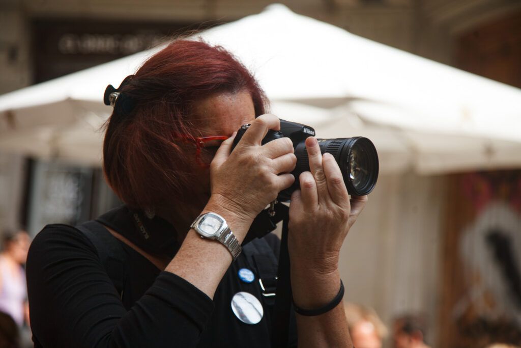 Fotógrafa de cabello rojo disparando con una cámara réflex en la calle