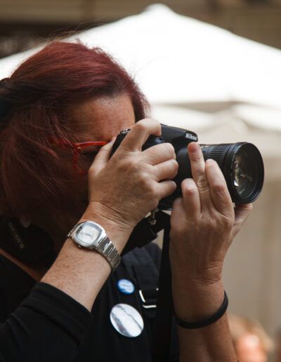 Fotógrafa de cabello rojo disparando con una cámara réflex en la calle