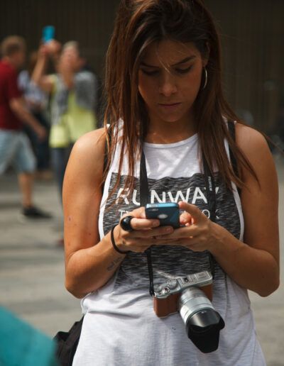 Chica joven mirando su cámara de fotos en una calle de Barcelona