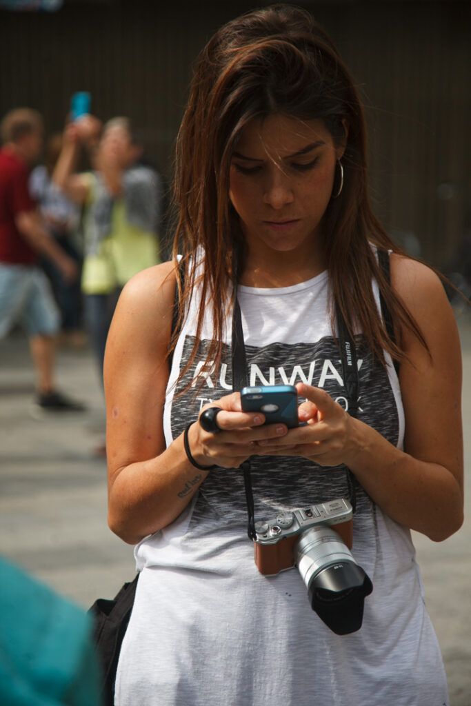 Chica joven mirando su cámara de fotos en una calle de Barcelona