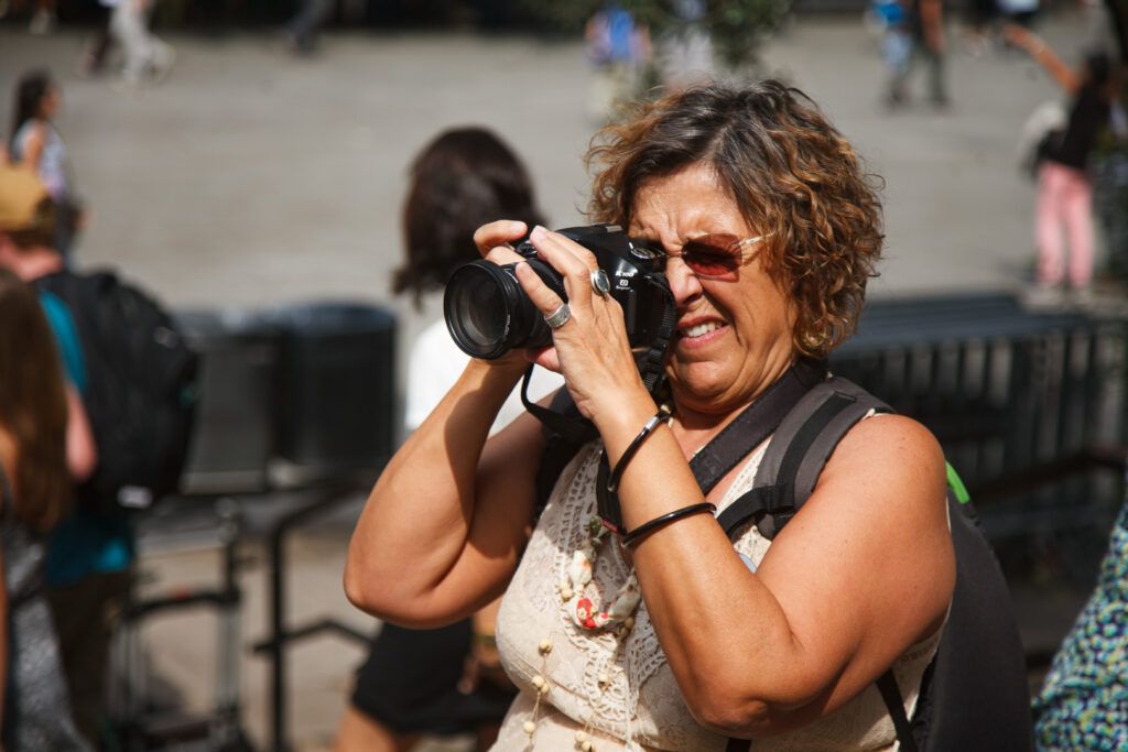 Fotógrafa con gafas de sol disparando con su cámara en una calle de Barcelona