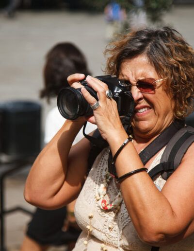 Fotógrafa con gafas de sol disparando con su cámara en una calle de Barcelona