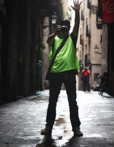 Persona con chaleco reflectante y el brazo en alto en un callejón urbano
