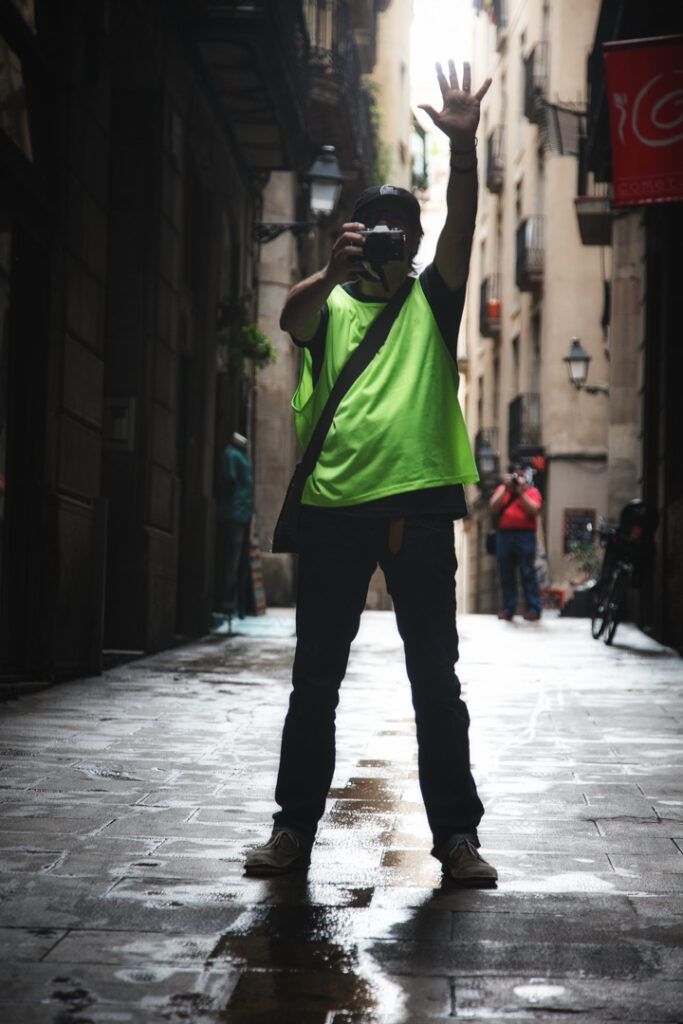 Persona con chaleco reflectante y el brazo en alto en un callejón urbano