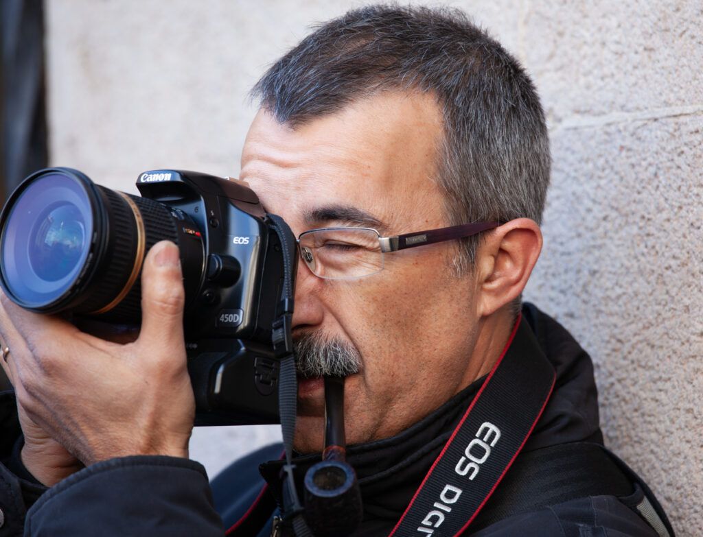 Hombre con gafas disparando con una cámara réflex Canon en primer plano