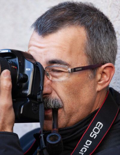 Hombre con gafas disparando con una cámara réflex Canon en primer plano