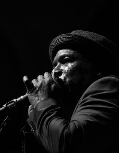 Armonicista con sombrero tocando ante el micrófono en directo, fotografía en blanco y negro