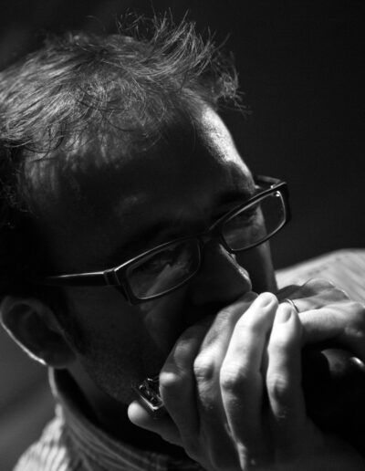 Armonicista con gafas tocando la armónica en primer plano, fotografía en blanco y negro