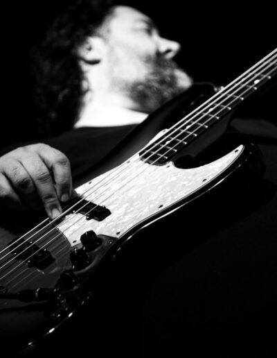 Bajista tocando un bajo eléctrico Fender Jazz Bass en directo, fotografía en blanco y negro