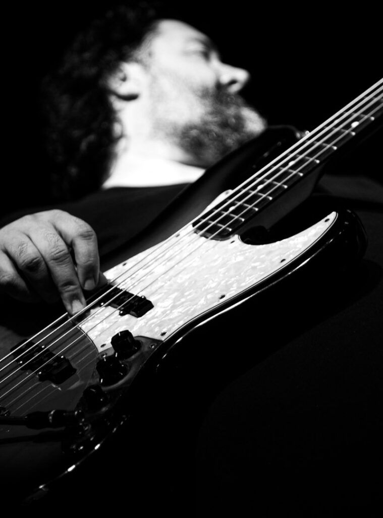 Bajista tocando un bajo eléctrico Fender Jazz Bass en directo, fotografía en blanco y negro