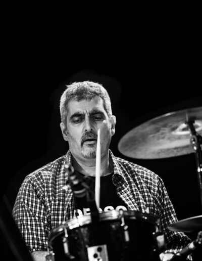 Baterista tocando en directo con baqueta y plato, fotografía en blanco y negro