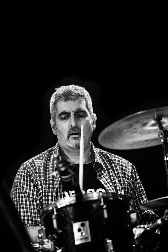 Baterista tocando en directo con baqueta y plato, fotografía en blanco y negro