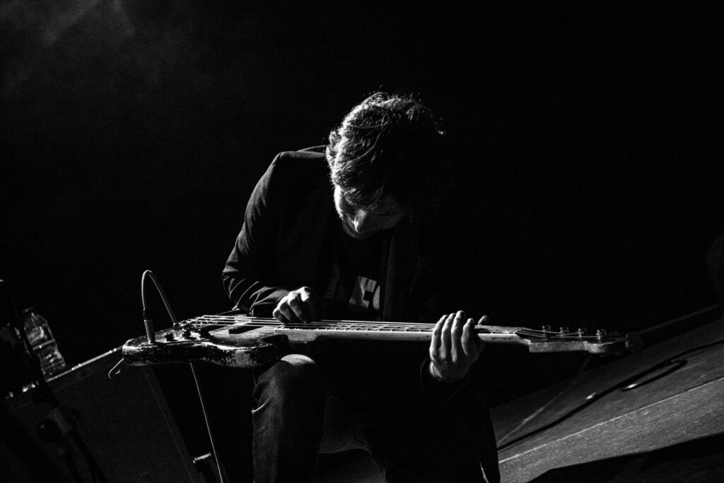 Cantante inclinado sosteniendo el micrófono en un momento intenso, concierto en blanco y negro