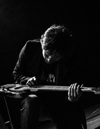 Cantante inclinado sosteniendo el micrófono en un momento intenso, concierto en blanco y negro