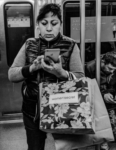Persona comprando online en Amazon con el teléfono en el metro, fotografía callejera de Lluís Ridao
