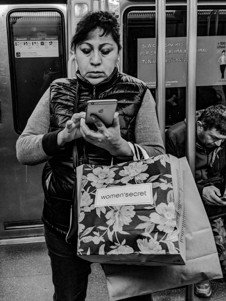 Persona comprando online en Amazon con el teléfono en el metro, fotografía callejera de Lluís Ridao