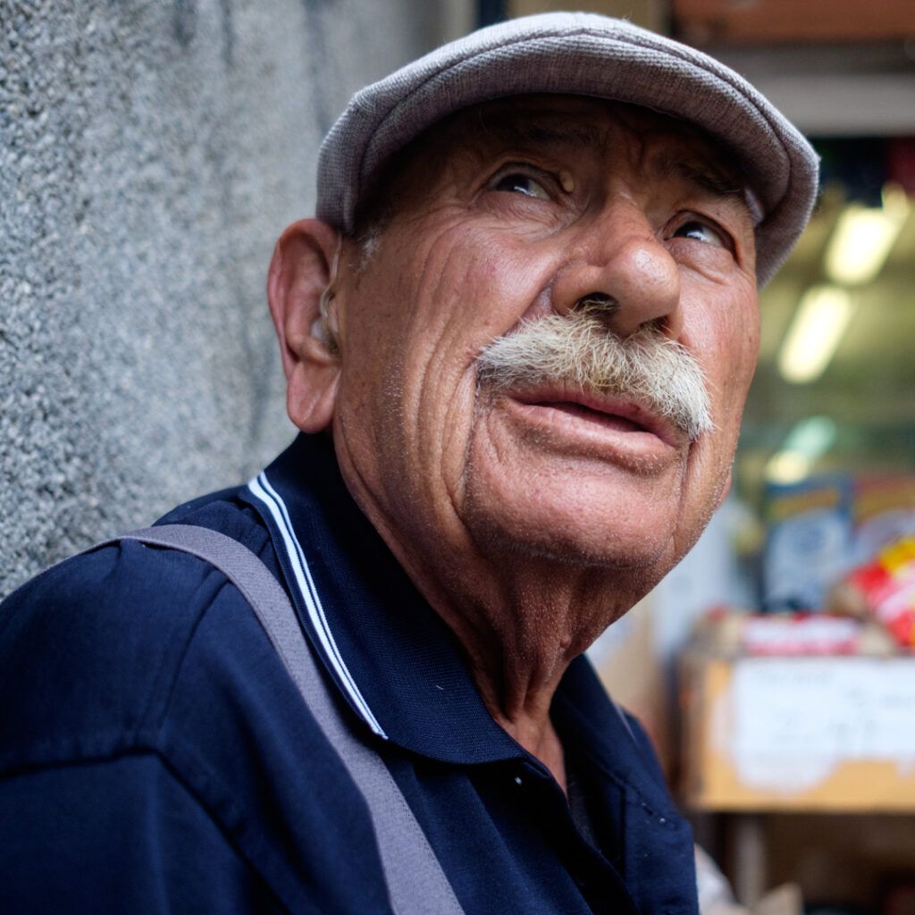 Retrato en contrapicado de un hombre mayor con gorra y bigote blanco