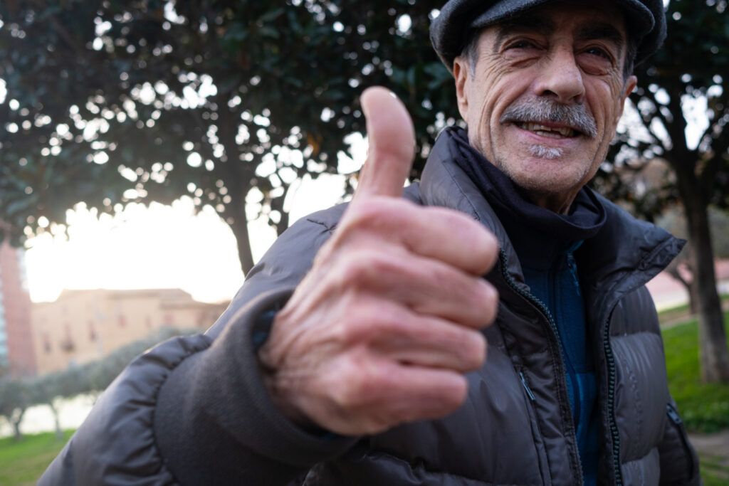 Retrato de un hombre con gorra y bigote levantando el pulgar