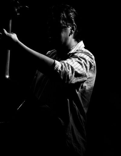 Contrabajista de perfil tocando el contrabajo en penumbra, fotografía en blanco y negro