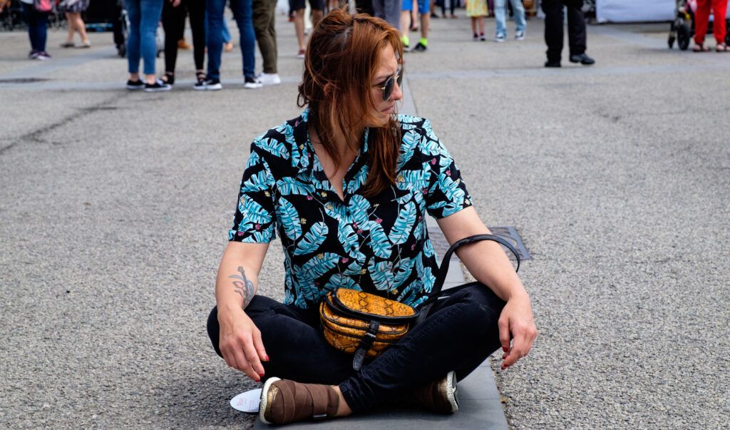 Mujer con gafas de sol sentada en el suelo en medio de la calle