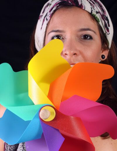 Mujer con pañuelo en la cabeza sosteniendo un molinillo de colores frente al rostro