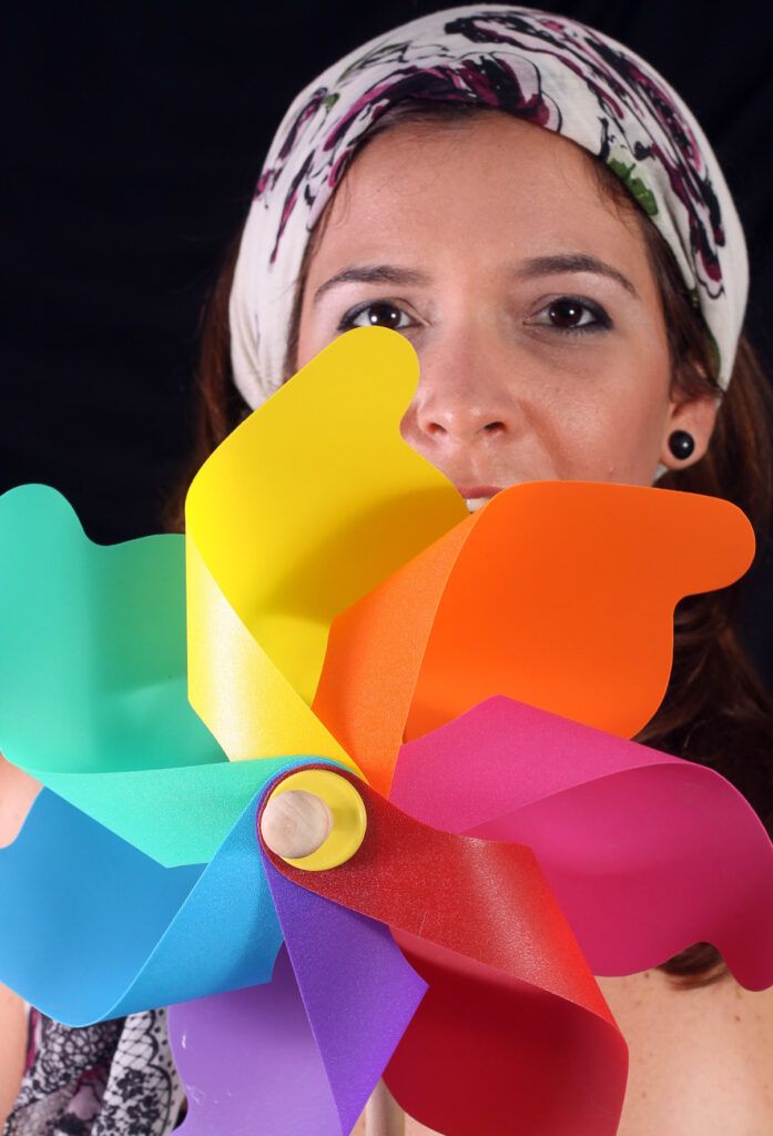 Mujer con pañuelo en la cabeza sosteniendo un molinillo de colores frente al rostro