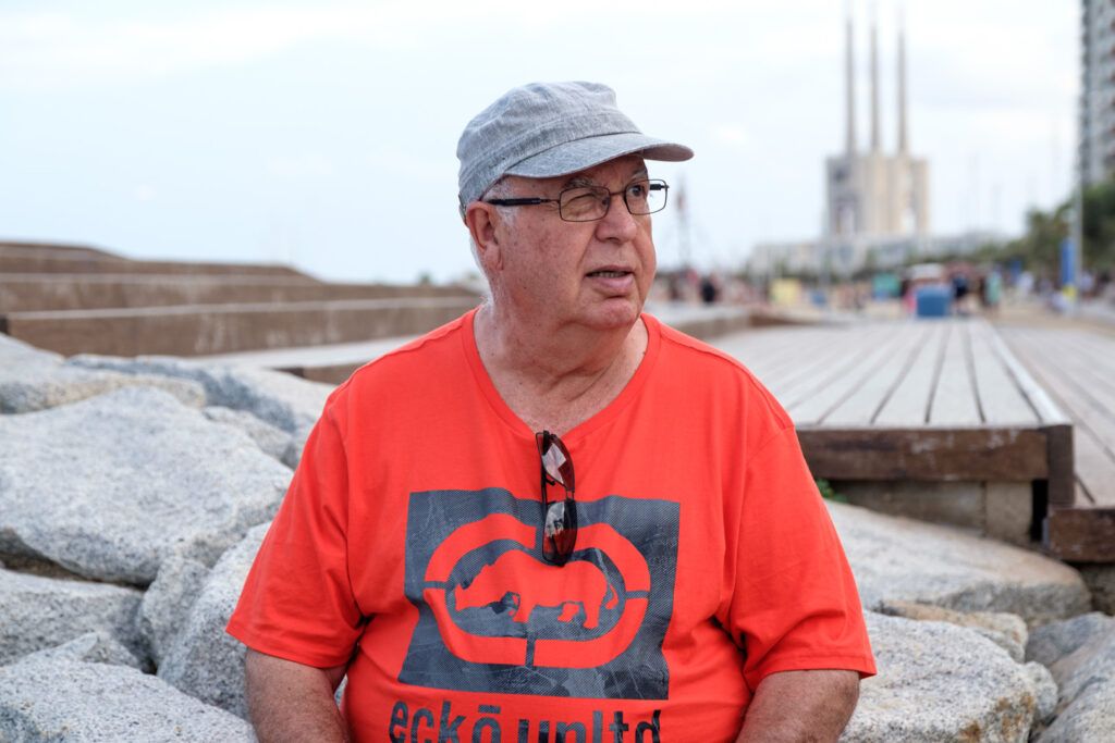 Retrato de un hombre con gorra y camiseta roja en el paseo marítimo de Badalona