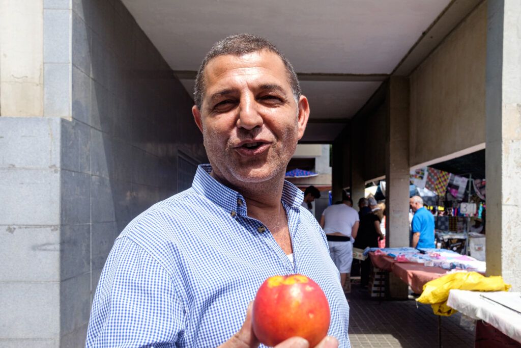Retrato de un hombre sonriente con una manzana en la mano en un mercado