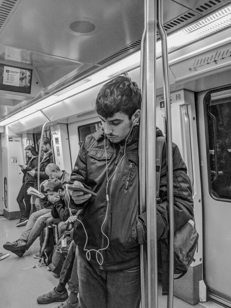 Persona escuchando música con auriculares en el metro, fotografía callejera de Lluís Ridao