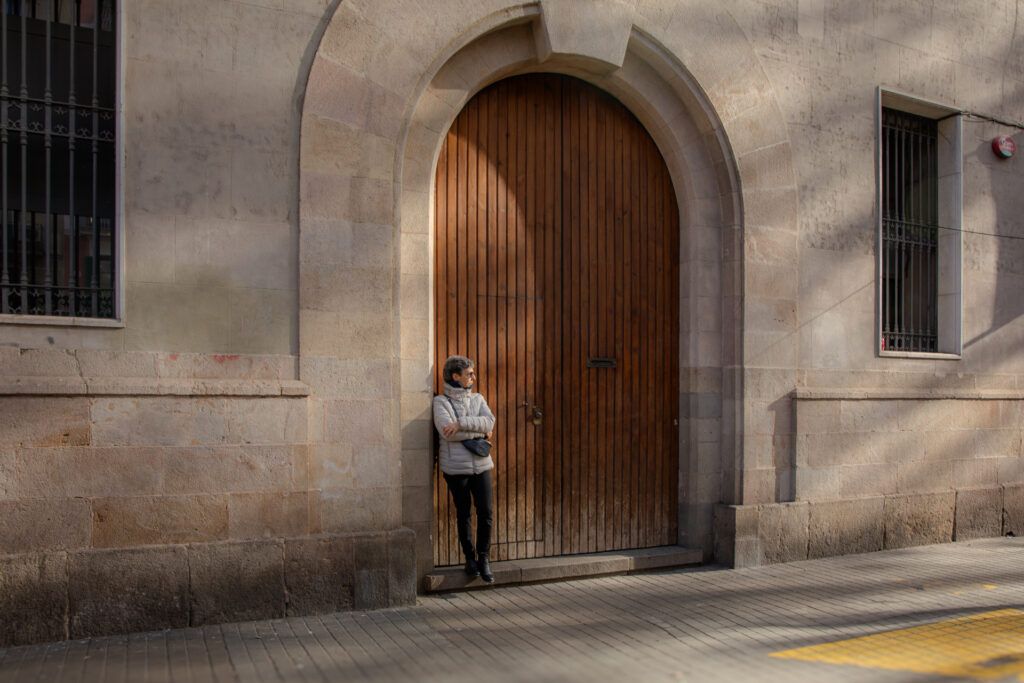 Persona de pie junto a un gran portón de madera en una calle vacía