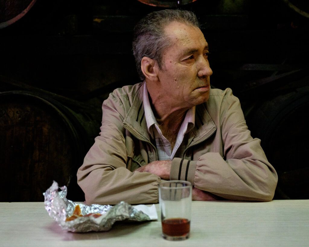 Hombre mayor con gafas apoyado, esperando en un bar
