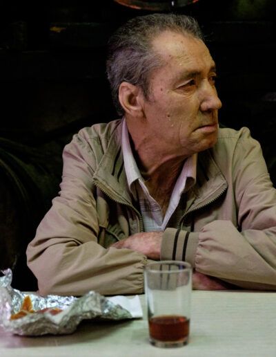 Hombre mayor con gafas apoyado, esperando en un bar