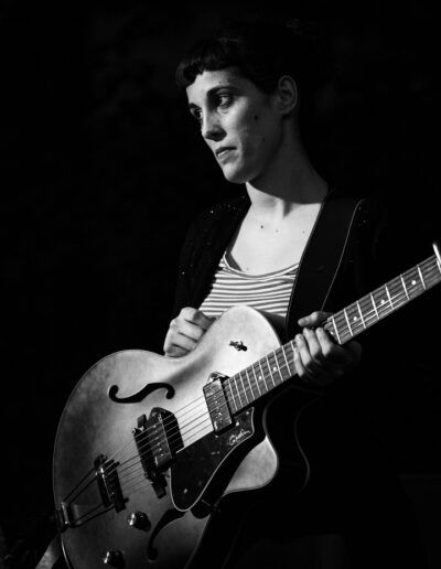 Guitarrista tocando una guitarra eléctrica apoyada sobre el regazo en directo, blanco y negro