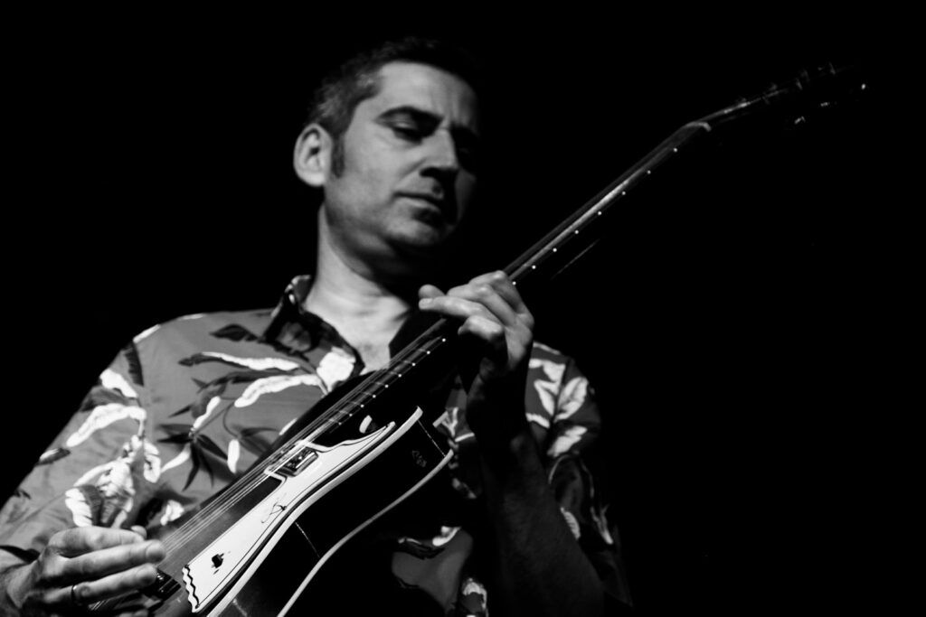 Guitarrista de jazz con guitarra de caja y camisa estampada, ojos cerrados, blanco y negro